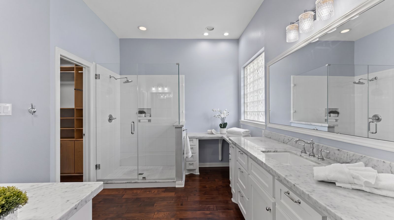 Primary bathroom with a glass walk-in shower and marble double vanity